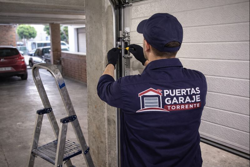 Técnico de Puertas Garaje Torrente revisando una puerta de garaje con escalera en una instalación real